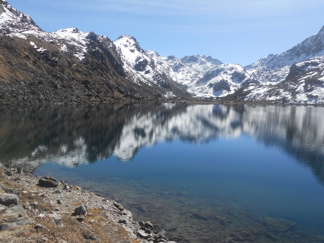 Clear lake reflecting snow-covered mountains.