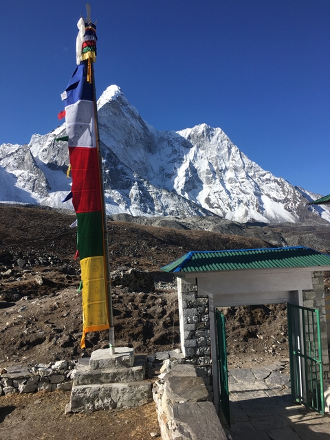 Colorful prayer flags in front of snowy mountains.