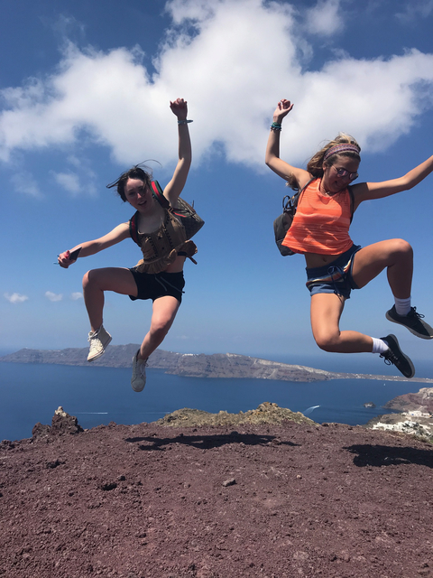 Two people jumping with a scenic ocean view.