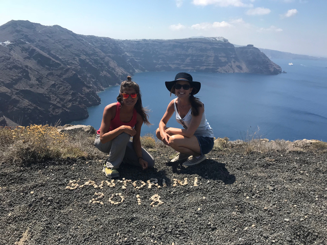 Women posing with ocean view and 'Santorini 2018' written.