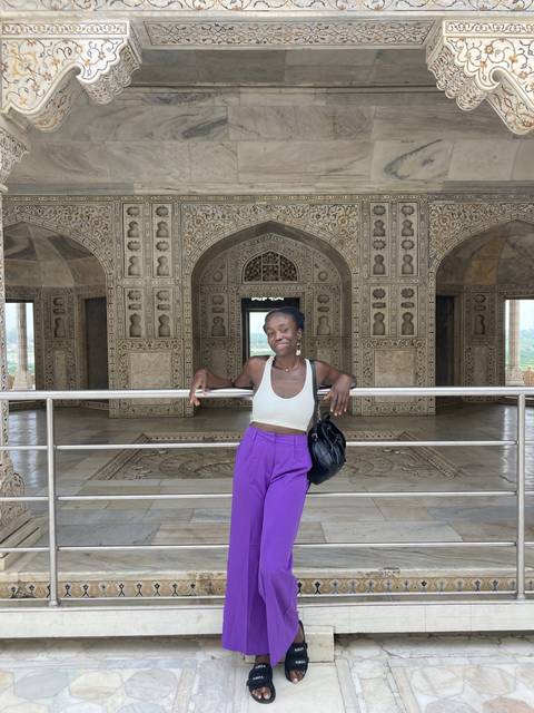 Person posing in front of intricately carved stone walls.