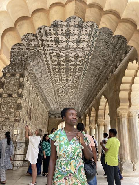 Person standing inside an ornately decorated corridor.