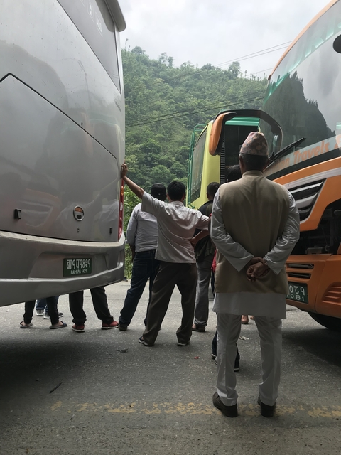 Group of men standing between buses.