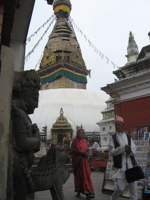 People posing near a stupa with colorful prayer flags.