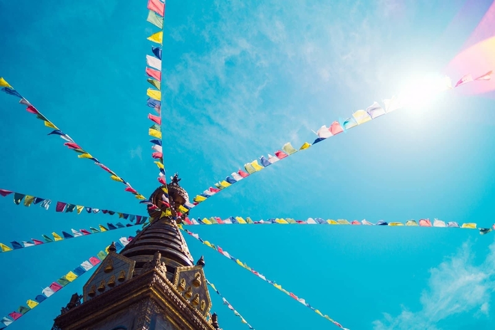       Colorful prayer flags stretched from a stupa under a clear blue sky.
  