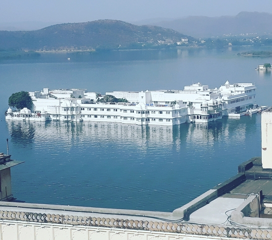       White building on a lake, known as the Lake Palace.
  