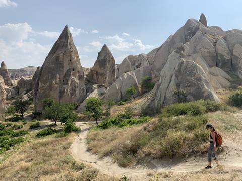       A woman hiking in a rocky landscape with unique formations.
  