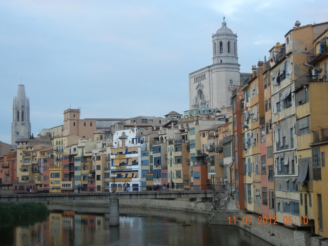 Colorful buildings along the river with a cathedral in the background.