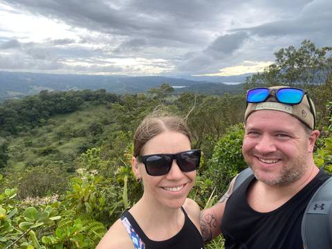 Couple posing with a panoramic view of forested hills.