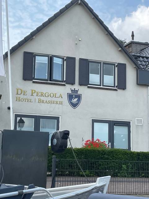       Building facade with 'De Pergola Hotel &amp; Brasserie' sign.
  
