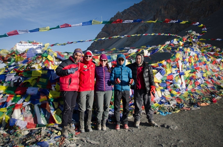       Group of people at a high-altitude pass with prayer flags.
  