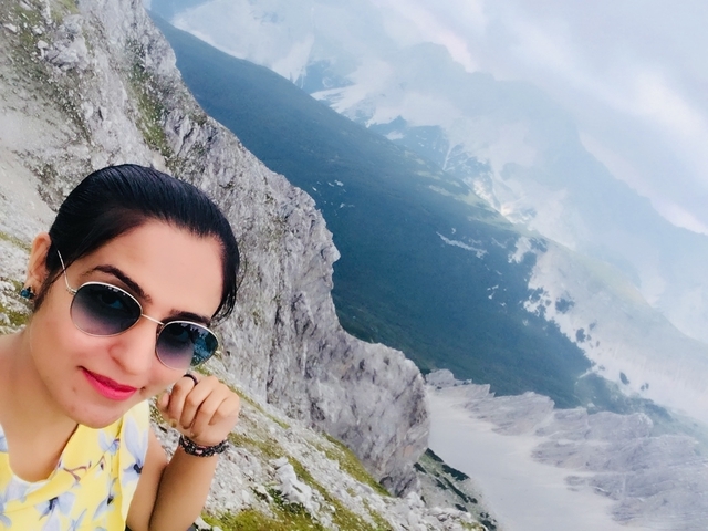 Selfie of a woman with sunglasses overlooking a scenic mountain view.