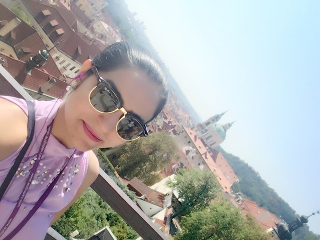 Woman with sunglasses taking a selfie with a city skyline.