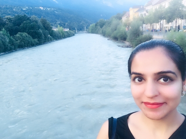 Selfie of a woman with a river and trees in the background.