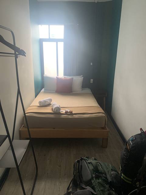       Simple hotel room with a bed and a backpack.
  