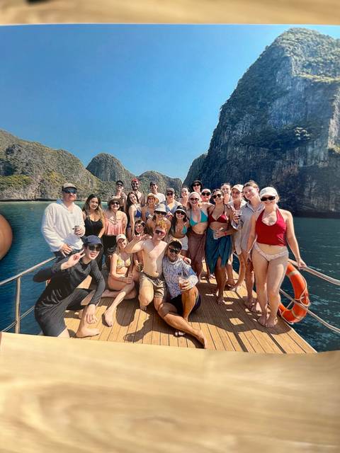 A large group of people on a boat with cliffs in the background.