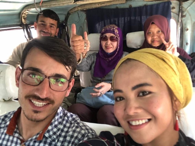       Group of people sitting inside a vehicle, smiling.
  