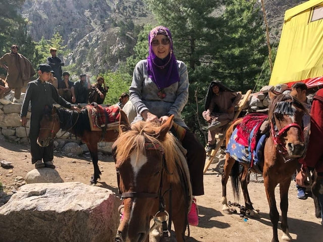       Woman on horseback in a rural outdoor setting.
  