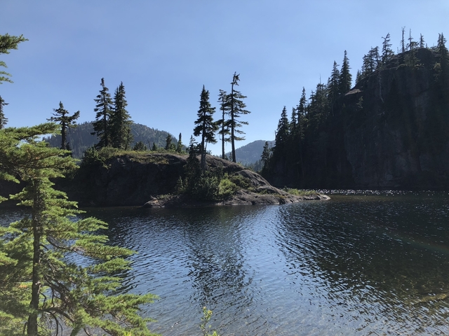 Calm lake surrounded by forested rocky hills.