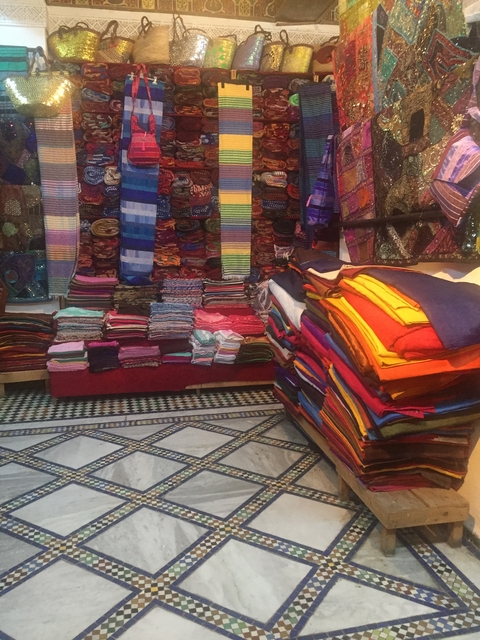       Colorful stacks of fabric within a market setting.
  