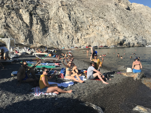       Crowded beach with people sunbathing and swimming.
  