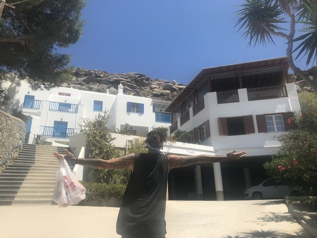       Person with arms outstretched in front of white buildings with blue accents.
  