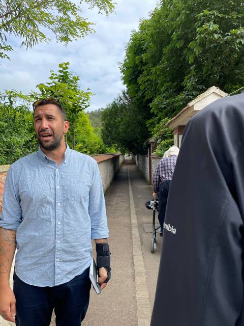       Person in a park with greenery on a sloped path.
  
