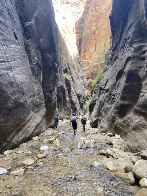       People hiking through a stony canyon passage.
  