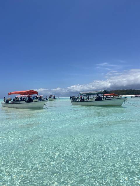       Boats on a clear ocean with a bright blue sky.
  
