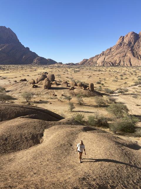       Person standing among large rock formations.
  