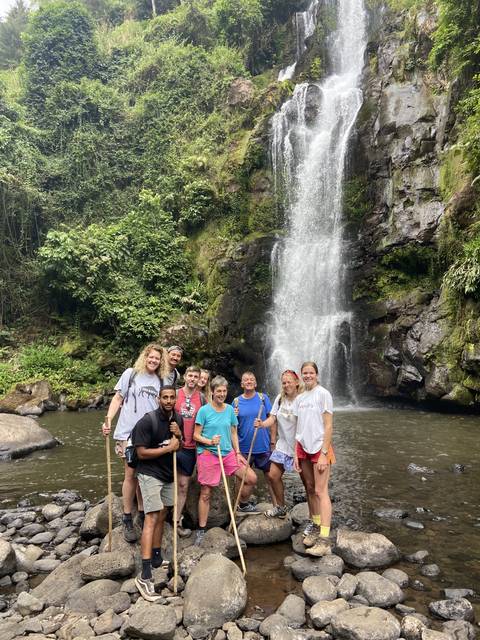       Group of people posing in front of a waterfall.
  