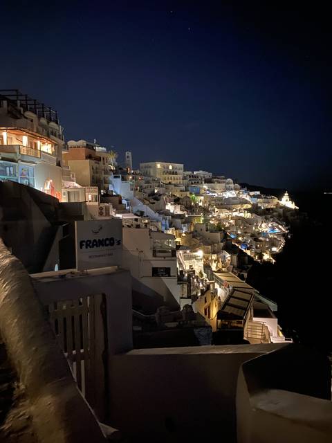 Night view of a hilltop town with lights illuminating the buildings.