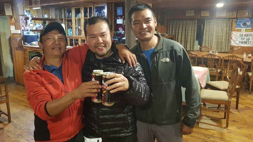 Three people holding drinks in a wooden interior.