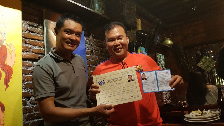 Two people holding a certificate in a restaurant setting.