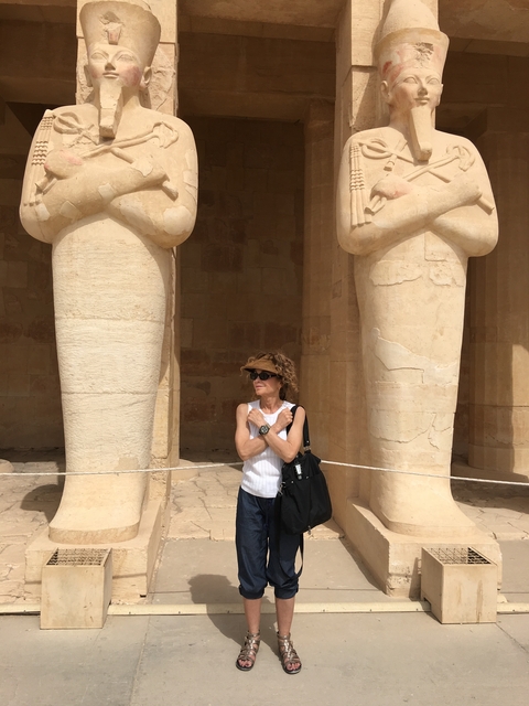       Woman posing between large ancient statues.
  