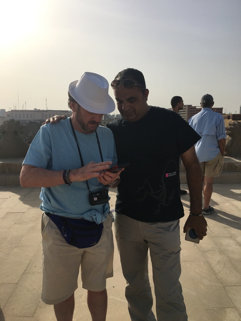 Two men looking at a smartphone, standing on a stone structure.