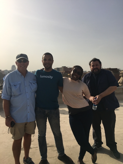       Group of four people posing outdoors with a city backdrop.
  