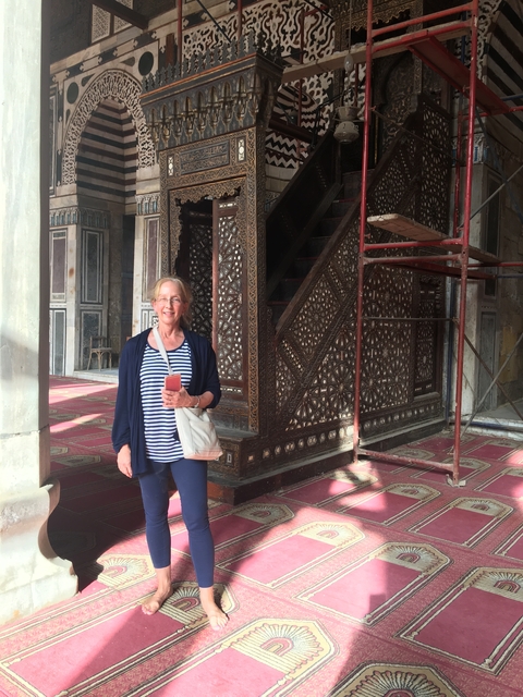 Woman standing inside an ornately decorated building with intricate designs.