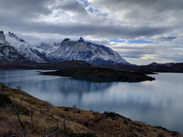       Panoramic view of a lake with surrounding mountains.
  