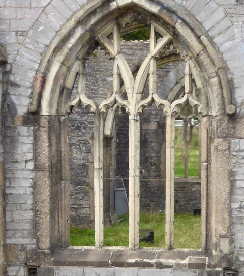 Ruins of a gothic cathedral with arched windows.