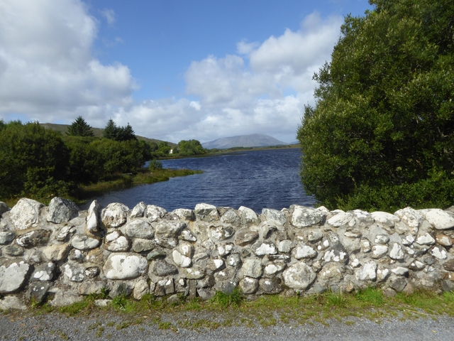       A scenic view of a lake with a stone wall in the foreground.
  