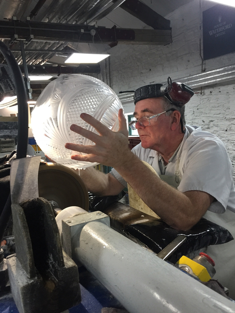       Craftsman inspecting glassware in a workshop.
  