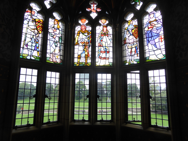       Stained glass windows depicting figures, with a view of a park.
  