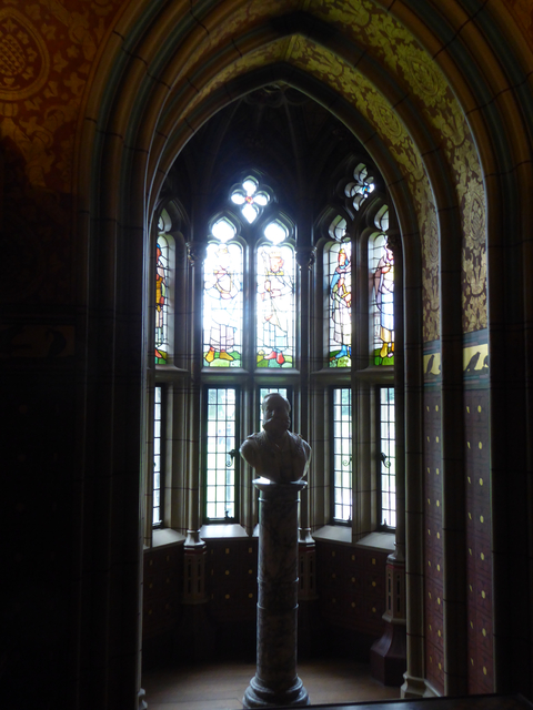       Bust statue with colorful stained glass windows.
  