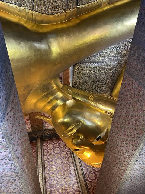       Reclining golden Buddha statue within a temple.
  