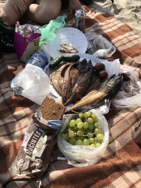 Traditional meal with fish, bread, and vegetables on a blanket.
