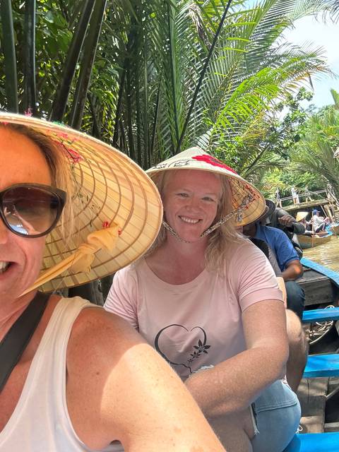       Women wearing traditional hats in a lush area.
  