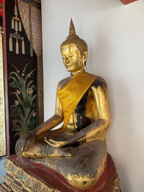 A golden Buddha statue with a yellow cloth wrap.