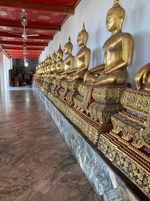 Row of golden Buddha statues in a temple.