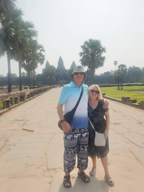       Two people posing in front of Angkor Wat
  